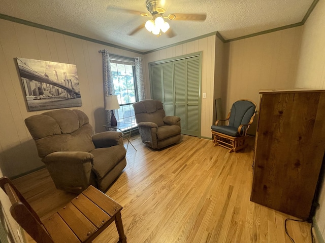 sitting room with a textured ceiling, ceiling fan, light wood-style floors, and crown molding