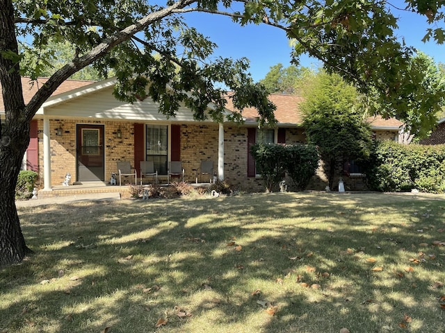 ranch-style home featuring brick siding, a front lawn, and a porch