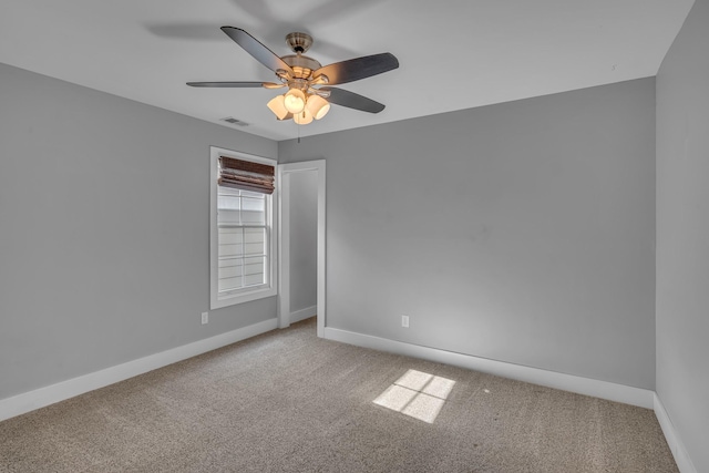 carpeted empty room featuring ceiling fan, visible vents, and baseboards