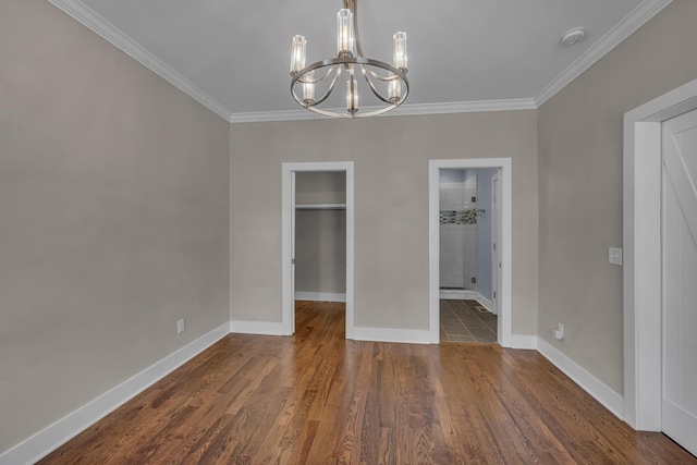 interior space with baseboards, a spacious closet, an inviting chandelier, and wood finished floors