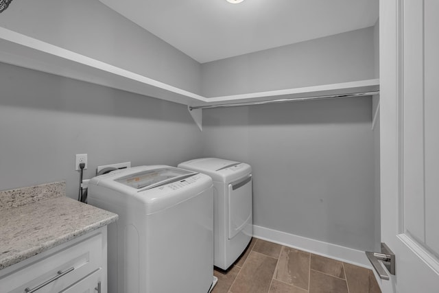 washroom featuring laundry area, wood finish floors, washing machine and clothes dryer, and baseboards