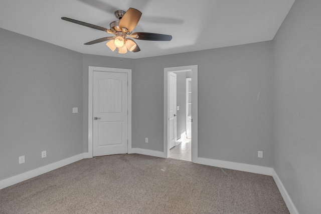 spare room with light carpet, ceiling fan, and baseboards