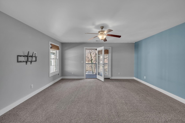 carpeted spare room featuring baseboards and a ceiling fan