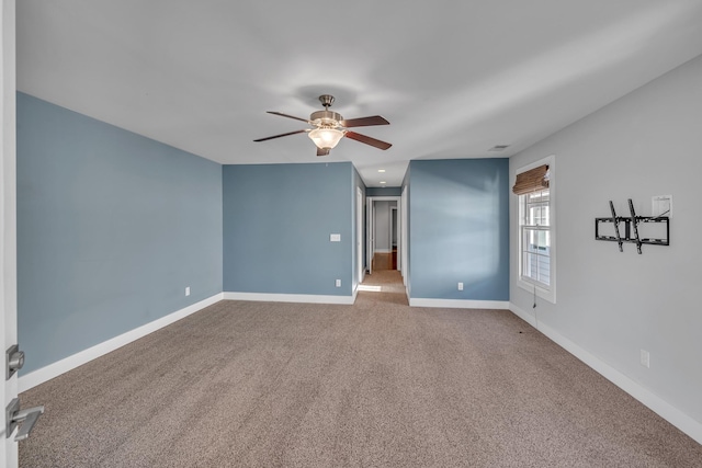 carpeted spare room with a ceiling fan and baseboards