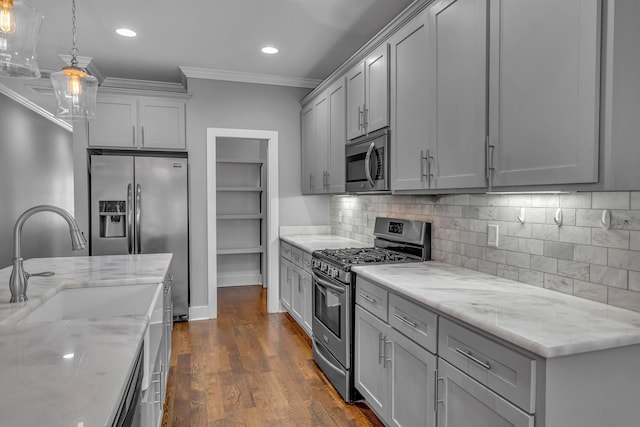 kitchen featuring tasteful backsplash, dark wood finished floors, gray cabinets, crown molding, and stainless steel appliances