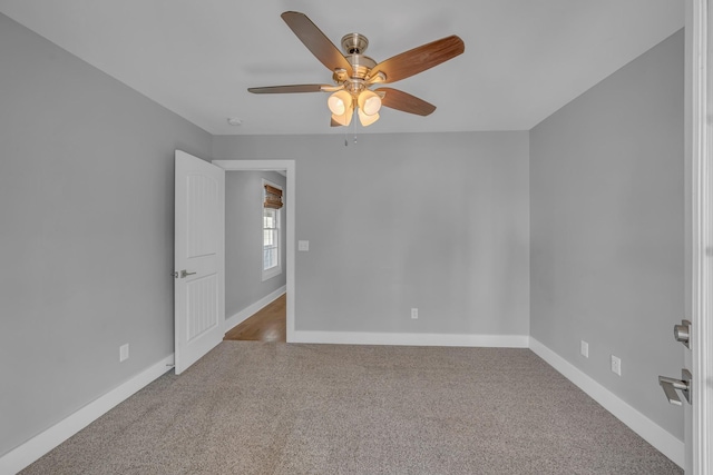 carpeted spare room featuring ceiling fan and baseboards