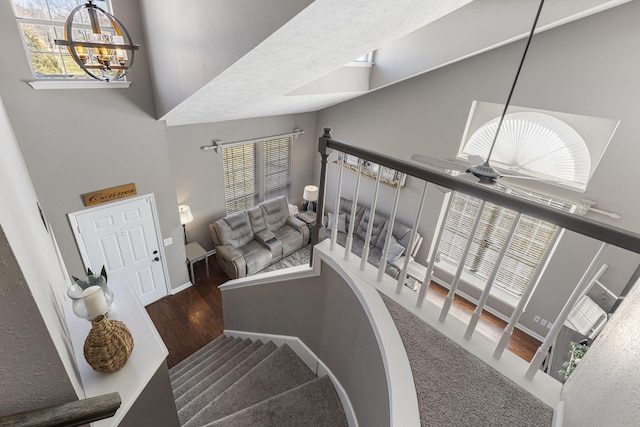 stairs with baseboards, an inviting chandelier, wood finished floors, and a towering ceiling