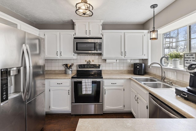 kitchen with tasteful backsplash, white cabinets, appliances with stainless steel finishes, and a sink