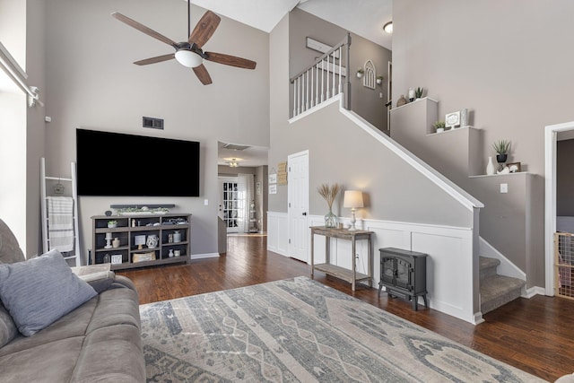 living area featuring visible vents, stairs, wainscoting, wood finished floors, and a ceiling fan