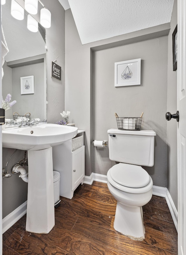 half bathroom featuring toilet, baseboards, and wood finished floors