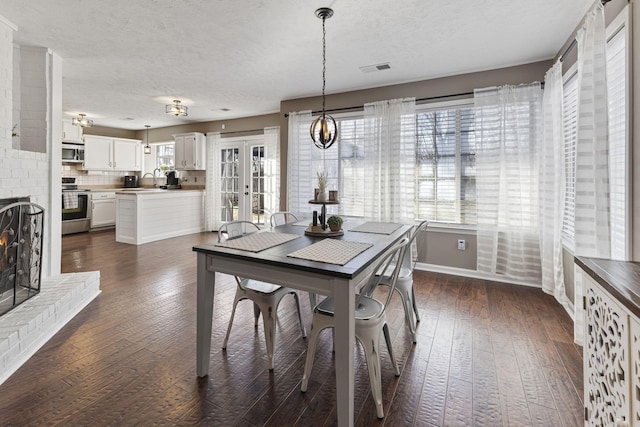 dining space featuring visible vents, a textured ceiling, dark wood-style floors, french doors, and baseboards