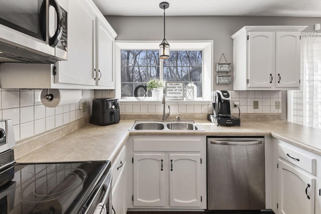 kitchen featuring white cabinets, stainless steel appliances, light countertops, and a sink