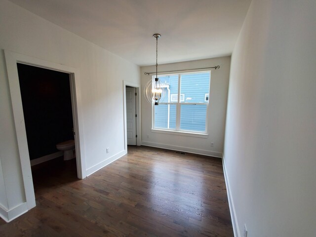 unfurnished dining area with visible vents, baseboards, dark wood-style flooring, and a notable chandelier