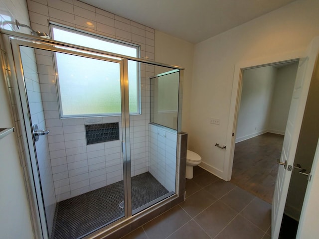 bathroom with a stall shower, plenty of natural light, tile patterned flooring, and toilet