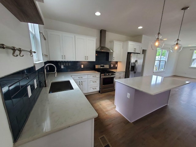 kitchen featuring stainless steel appliances, tasteful backsplash, a kitchen island, a sink, and wall chimney exhaust hood