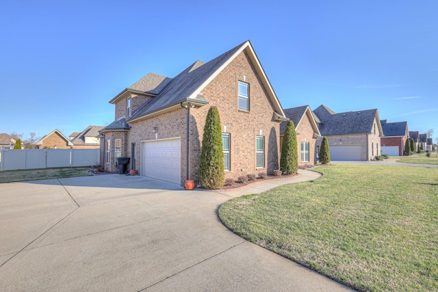 view of front facade with brick siding, a shingled roof, concrete driveway, fence, and a front yard