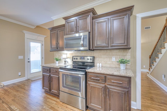 kitchen with stainless steel appliances, light wood finished floors, visible vents, and crown molding