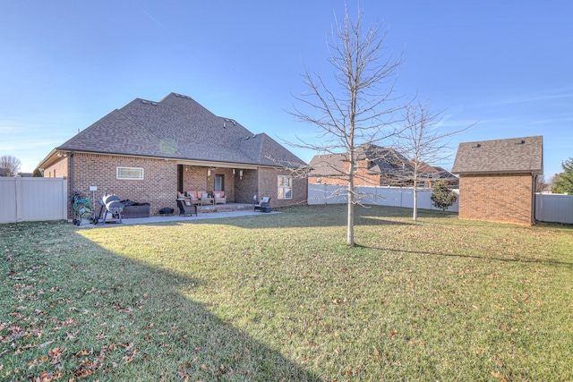 back of property with a fenced backyard, brick siding, a yard, roof with shingles, and a patio area