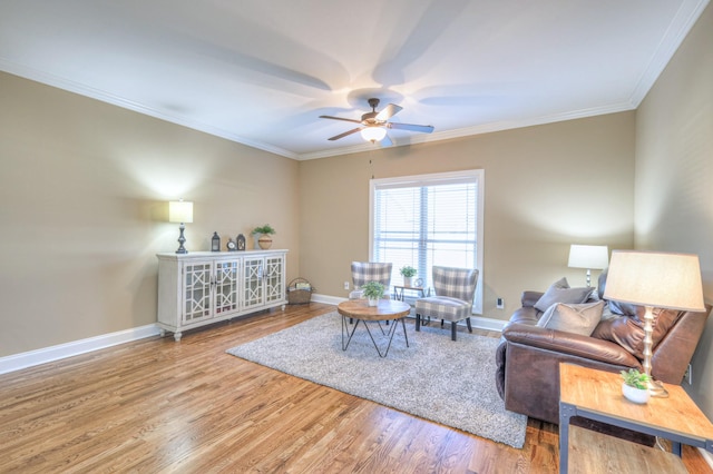 living area featuring a ceiling fan, crown molding, baseboards, and wood finished floors