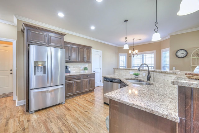 kitchen with stainless steel appliances, a sink, light wood-style flooring, and dark brown cabinets