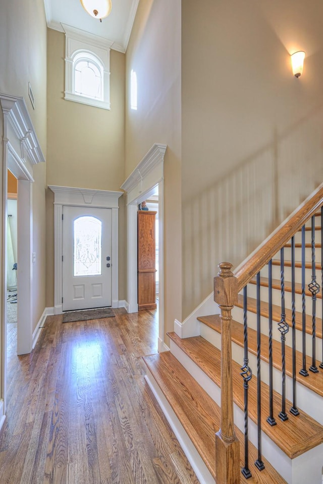 entrance foyer featuring plenty of natural light, stairway, crown molding, and wood finished floors