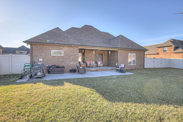 back of property featuring a shingled roof, a lawn, and a patio area