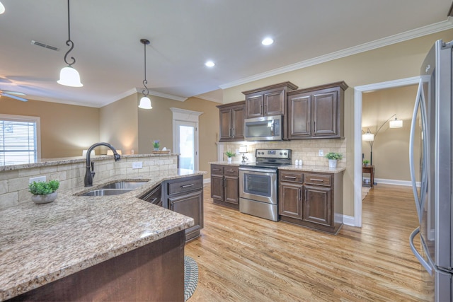 kitchen featuring dark brown cabinetry, a sink, visible vents, light wood-style floors, and appliances with stainless steel finishes