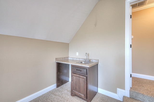 bar with baseboards, a sink, lofted ceiling, and light colored carpet