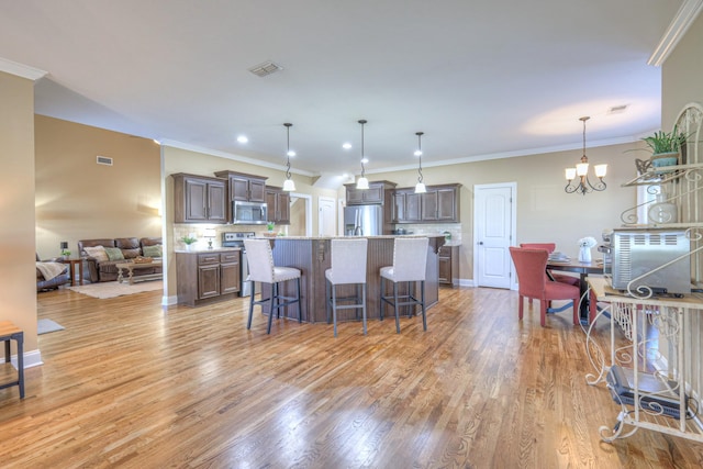 kitchen with a breakfast bar, a notable chandelier, light wood finished floors, stainless steel appliances, and visible vents