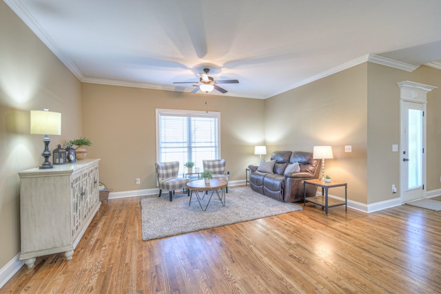 living room with light wood finished floors, baseboards, ornamental molding, and a ceiling fan