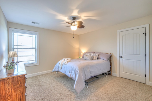 bedroom with light carpet, ceiling fan, visible vents, and baseboards