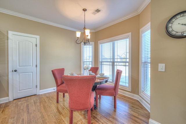 dining room with a chandelier, wood finished floors, visible vents, baseboards, and crown molding