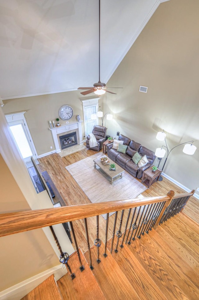 unfurnished living room with baseboards, visible vents, wood finished floors, high vaulted ceiling, and a high end fireplace