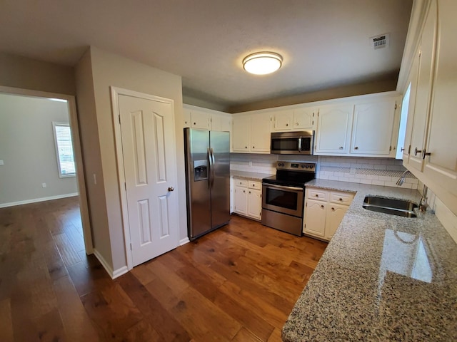 kitchen featuring visible vents, decorative backsplash, dark wood-style floors, appliances with stainless steel finishes, and a sink