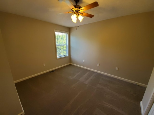 spare room with visible vents, dark carpet, a ceiling fan, and baseboards