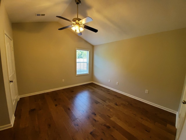 empty room featuring dark wood-style floors, vaulted ceiling, a ceiling fan, and baseboards