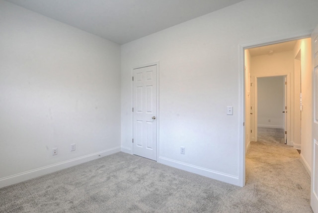 unfurnished bedroom with light carpet and baseboards