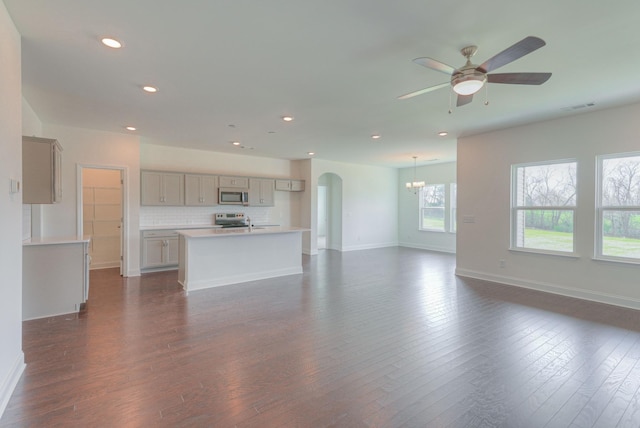 unfurnished living room with arched walkways, recessed lighting, dark wood-style flooring, visible vents, and baseboards