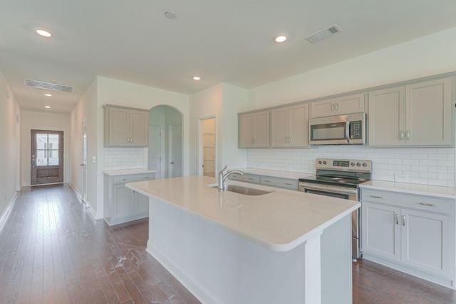 kitchen with a center island with sink, visible vents, gray cabinets, stainless steel appliances, and a sink