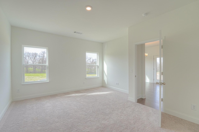 spare room with baseboards, visible vents, and light colored carpet