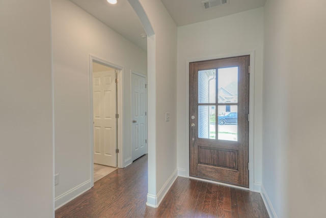 entrance foyer with arched walkways, visible vents, baseboards, and wood finished floors