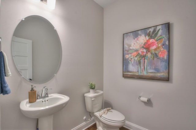 bathroom featuring toilet, baseboards, and a sink