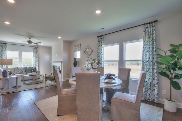 dining space featuring a fireplace, baseboards, wood finished floors, and recessed lighting