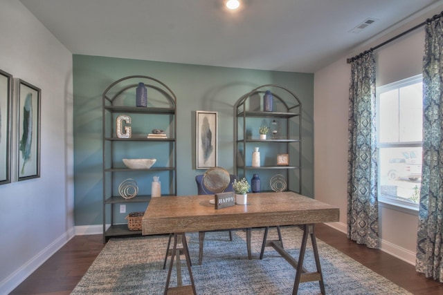 home office with dark wood-style floors, a healthy amount of sunlight, visible vents, and baseboards