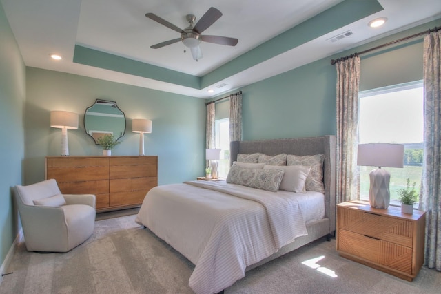 carpeted bedroom with ceiling fan, visible vents, a tray ceiling, and recessed lighting