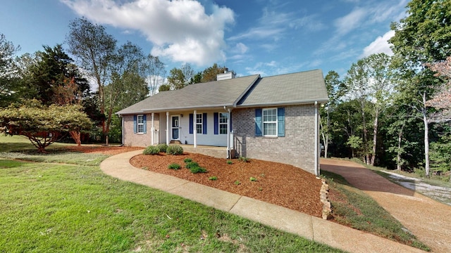 ranch-style home with brick siding, a chimney, and a front yard