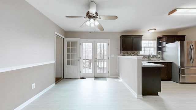 kitchen featuring dark brown cabinetry, light countertops, french doors, freestanding refrigerator, and a sink