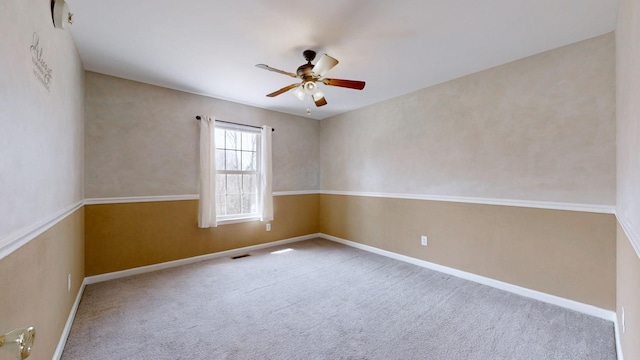 carpeted spare room with visible vents, a ceiling fan, and baseboards