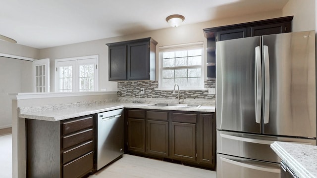 kitchen with a sink, stainless steel appliances, backsplash, and light countertops