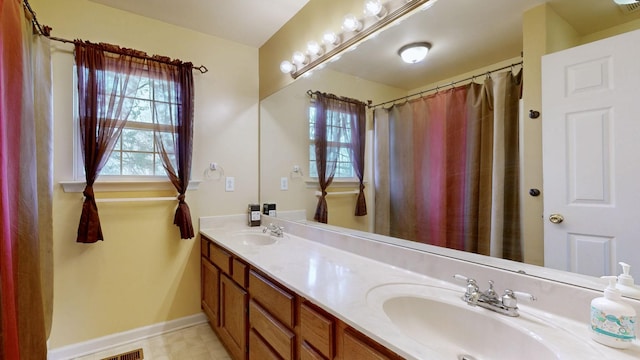 bathroom with double vanity, baseboards, and a sink